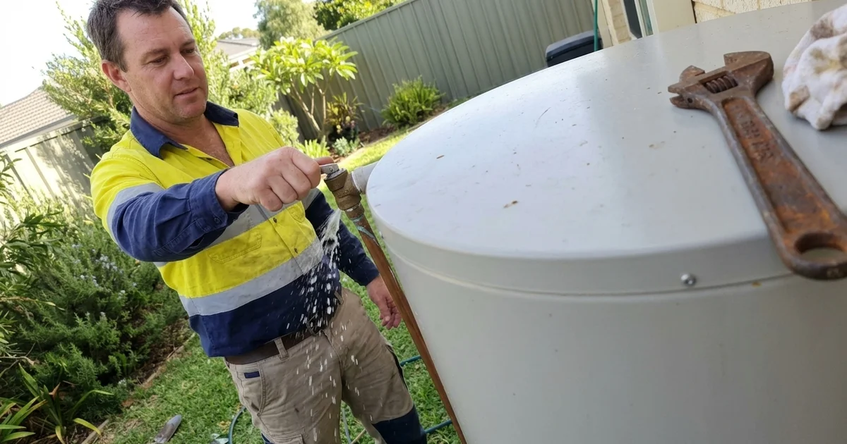 Perth plumber checking the relief valve on an outdoor hot water tank in early spring