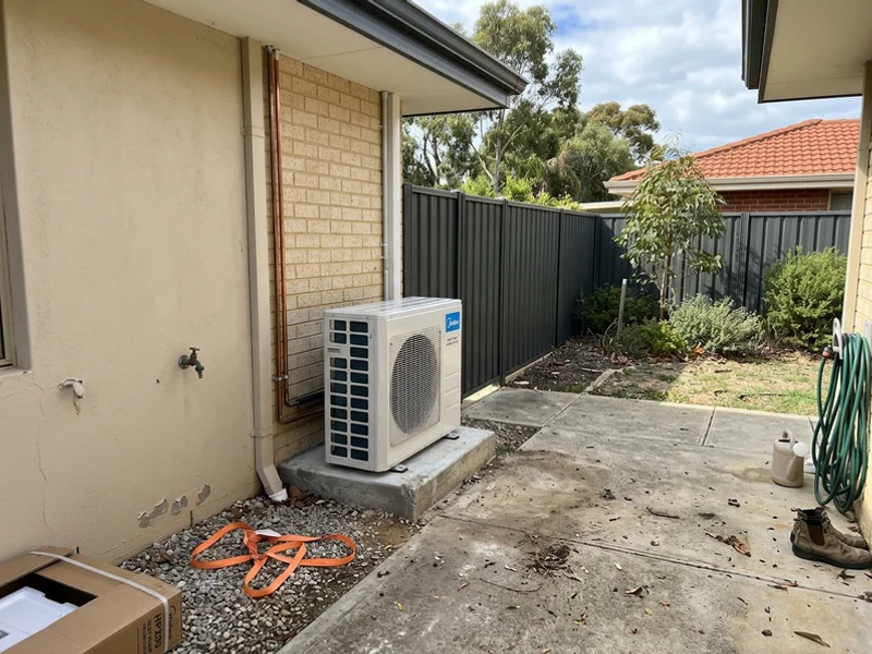 Heat pump hot water unit on a concrete pad with clear airflow