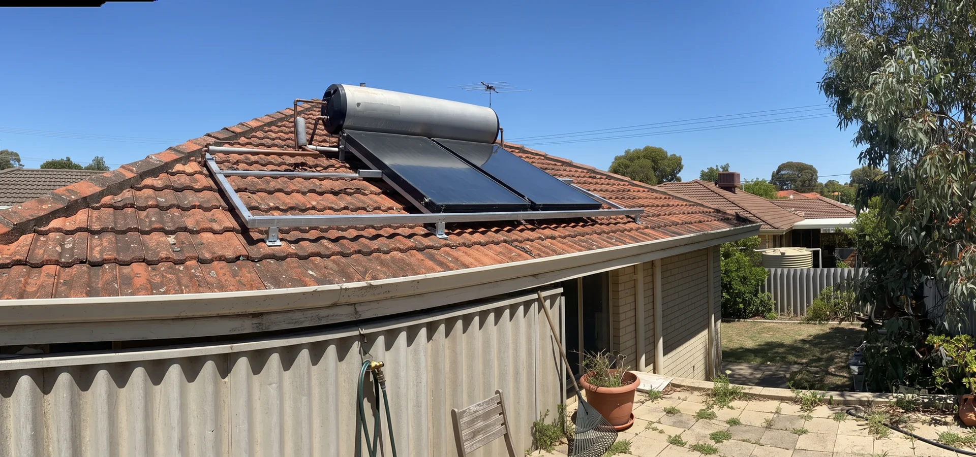 Solar hot water collectors and tank mounted on the tiled roof of a Perth home